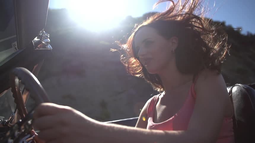 A woman drives a car as she smiles