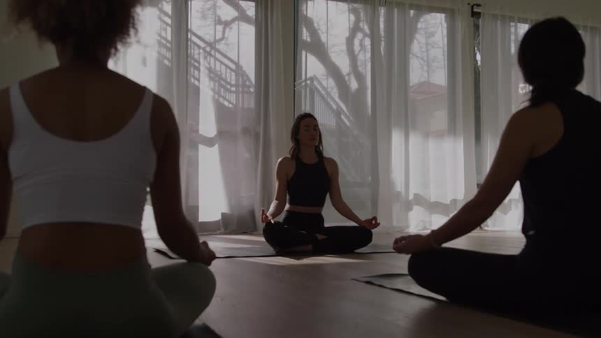 Group practices meditation seated in a circle in a bright studio