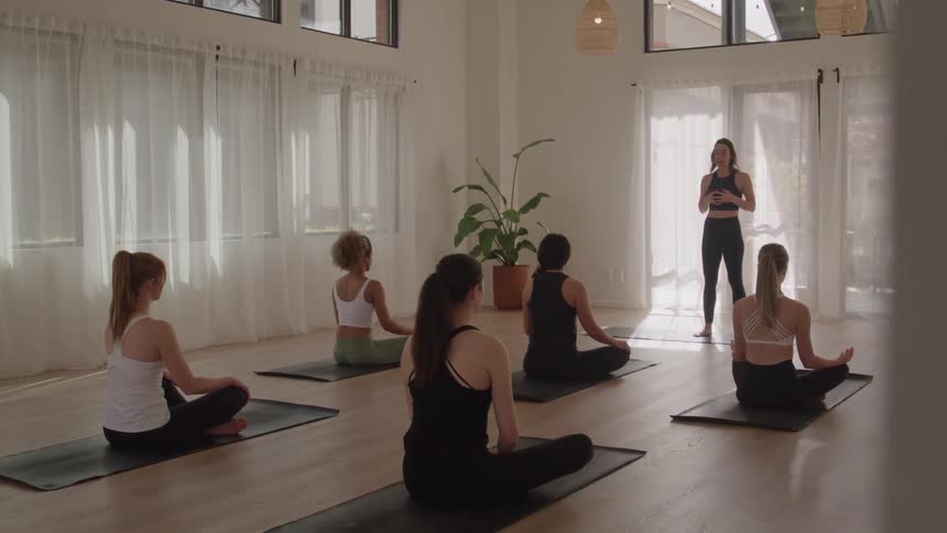 Group practices seated yoga on mats while the instructor guides the class