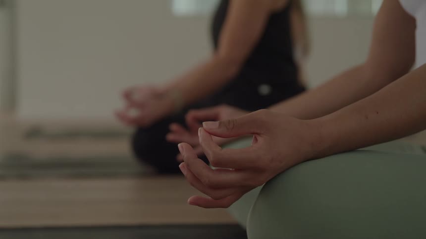 Hands rest on knees in a meditation position during a yoga practice