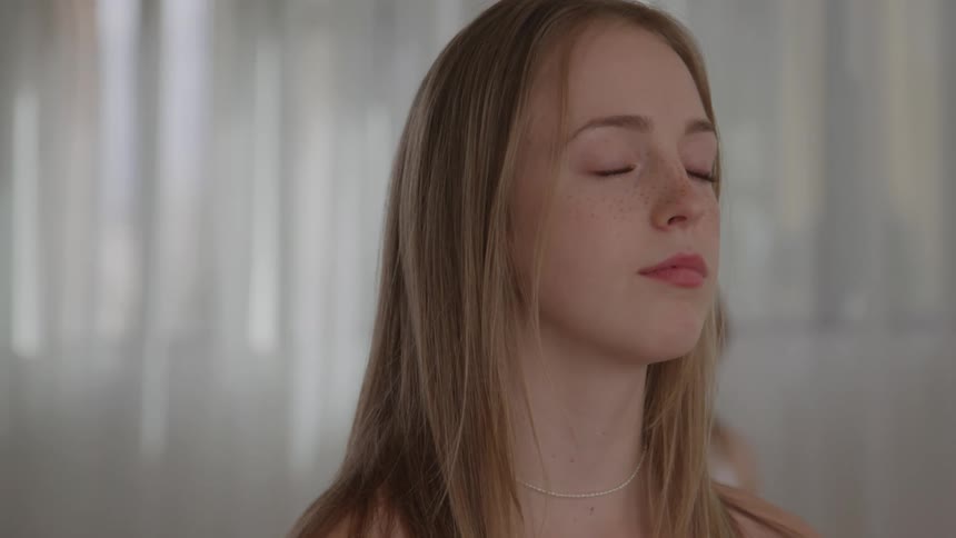 Woman meditates with closed eyes during group yoga practice