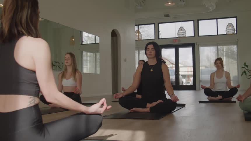 Group remains in a seated meditation pose in a yoga studio