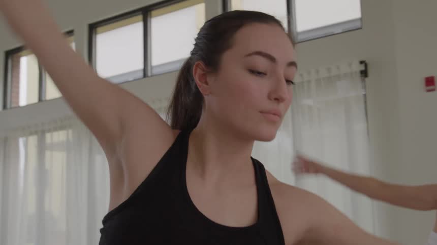 Women move through a yoga pose while exercising indoors during the day