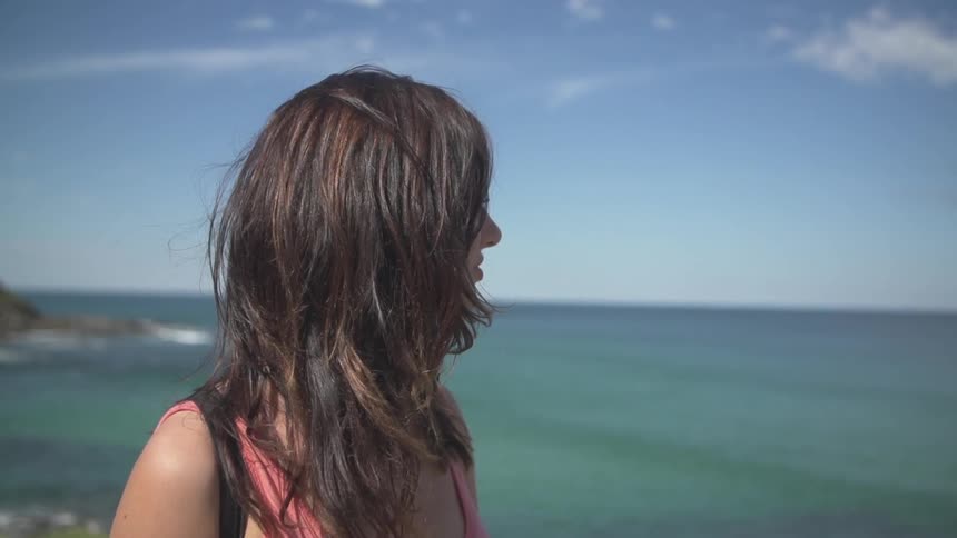 Woman walking as she looks at the ocean