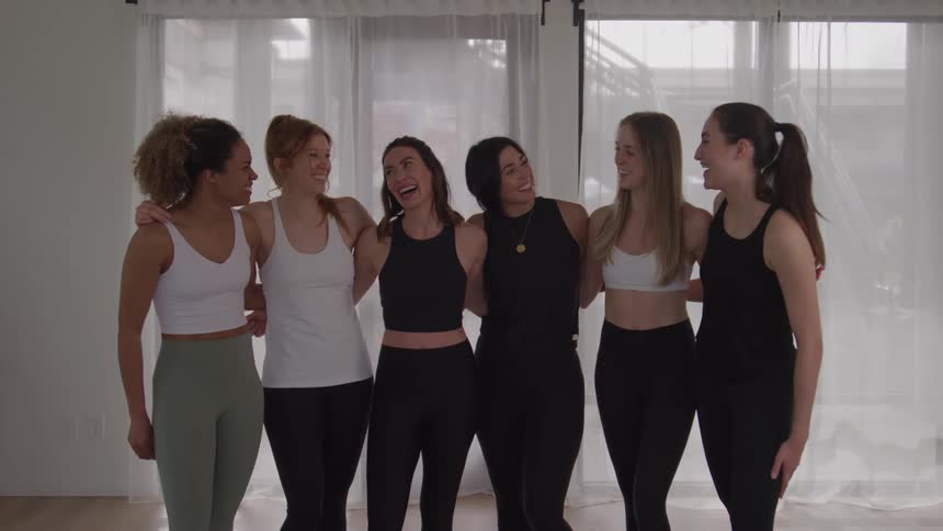 The women are standing side by side laughing and talking