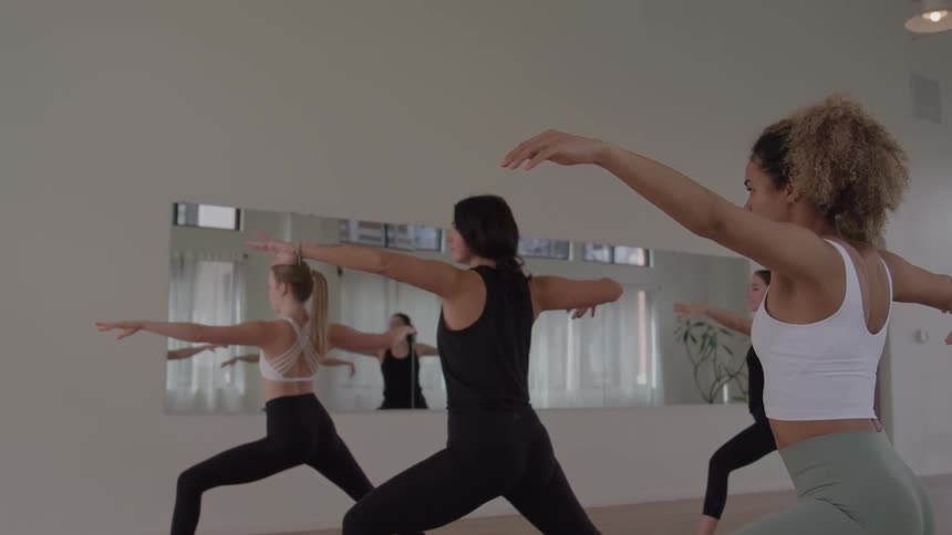 Group holds warrior pose with focus during a yoga class