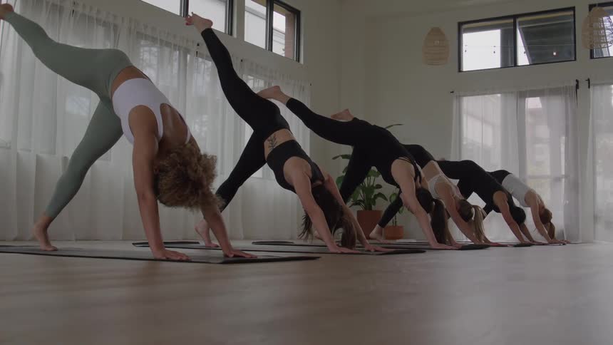 The women are doing yoga and kicking their legs up in the air