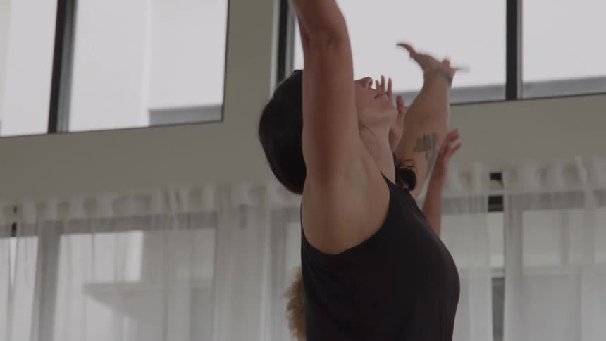 Woman performs a stretch with arms raised during a yoga session