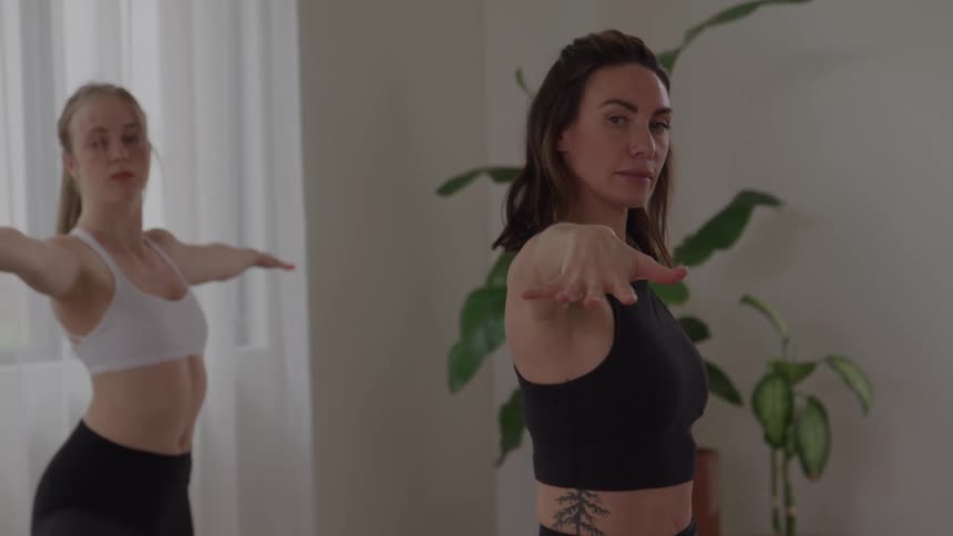 Women extend their arms maintaining aligned posture during a yoga class