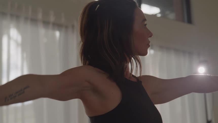 A woman is stretching indoors doing yoga