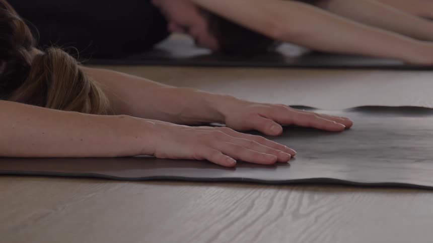 The women are doing yoga together and leaning on the mats