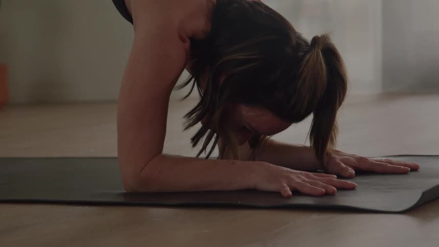 The woman is doing yoga and leaning her hands on the floor