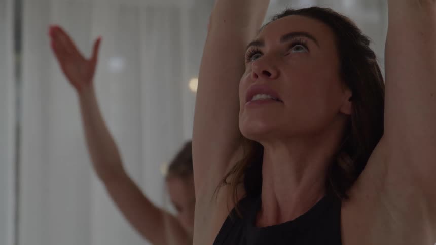 Woman focuses on a stretch with arms raised during yoga practice