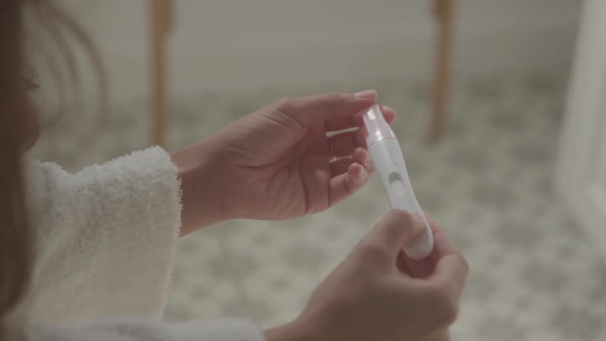 Hands hold a pregnancy test in a bathroom setting