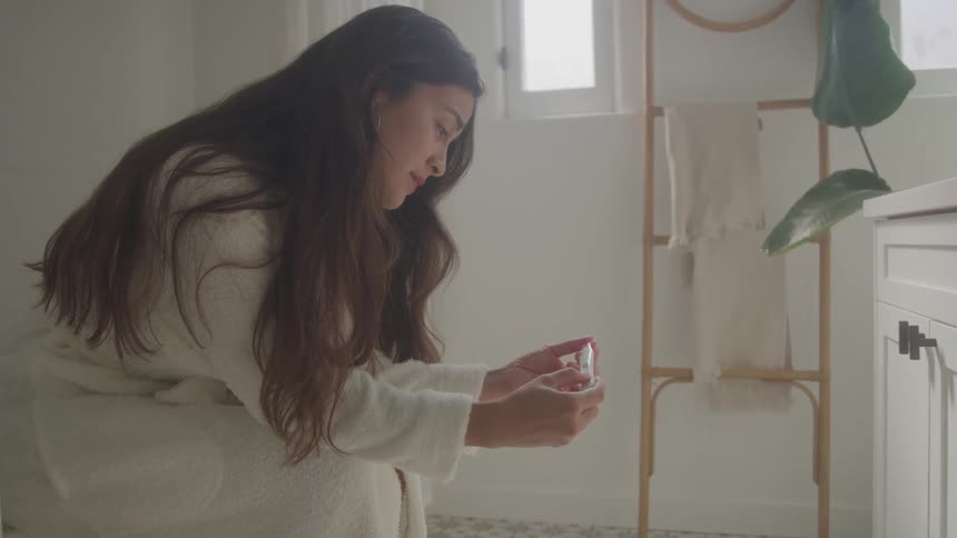 The woman is looking at a pregnancy test in the bathroom