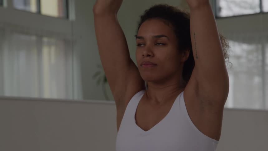 Woman keeps her hands together in a prayer position during a yoga practice