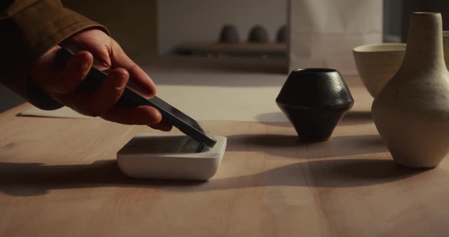 Hand using a spatula on a container beside ceramic pieces