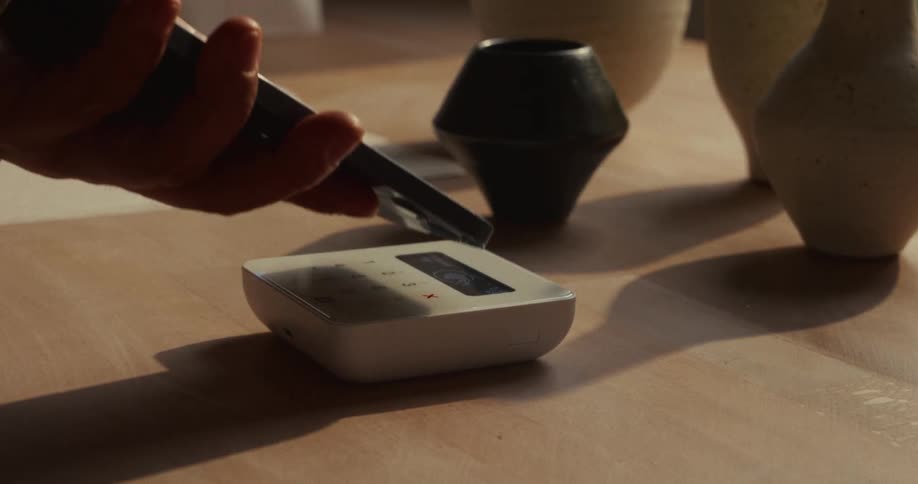 Hand making a contactless payment with a smartphone on a card reader