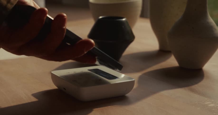 A person pays with their phone on a payment machine inside a pottery shop