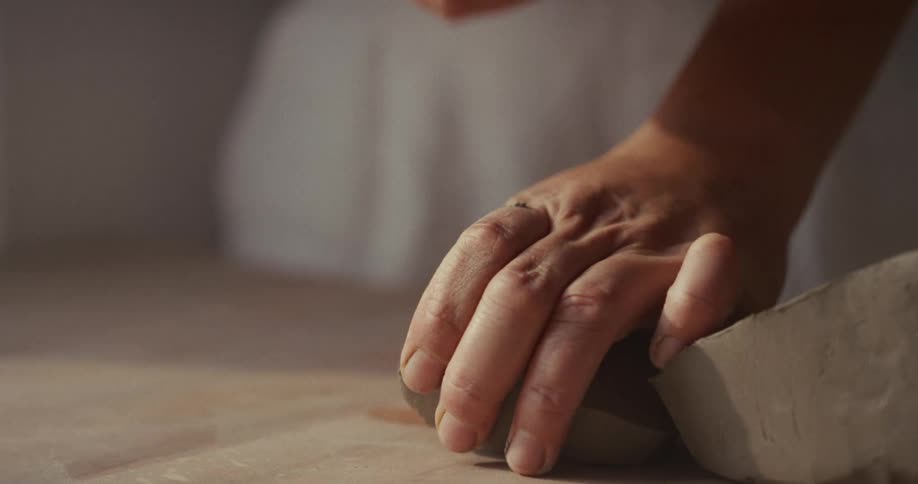 Hands dividing a piece of clay on the work surface
