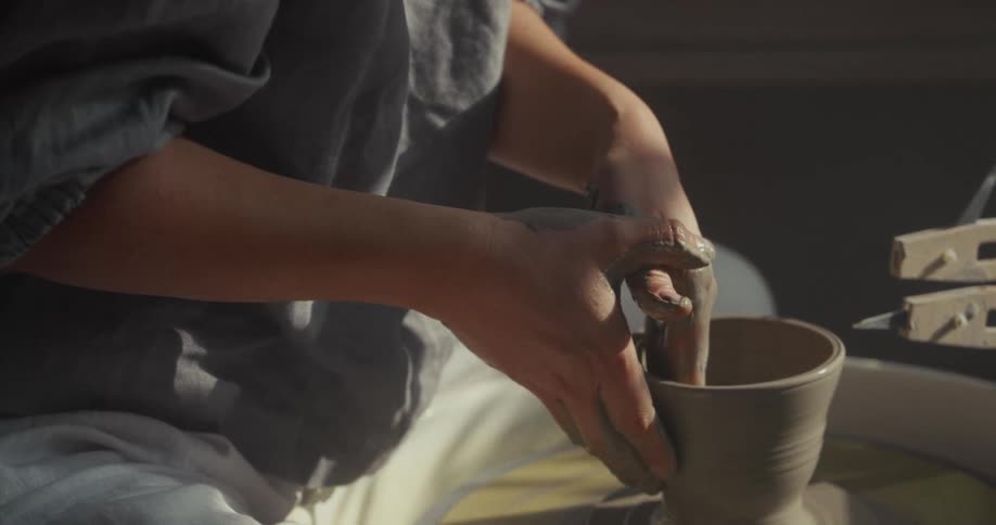 Close up of a young woman moulding pottery on a potters wheel indoors during daytime