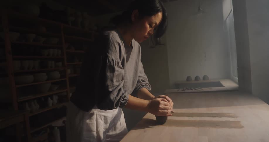 Person focused on kneading clay on the worktable