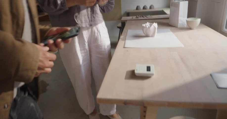 Man makes a payment in a handmade ceramics store with a saleswoman next to him