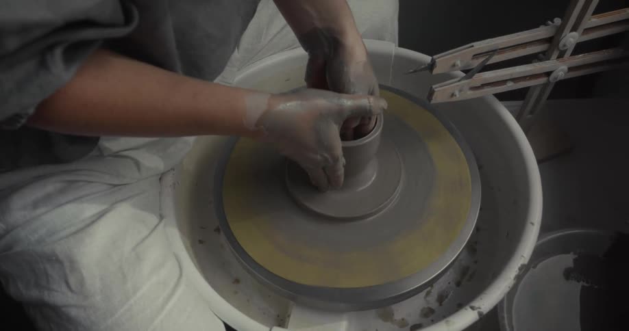 Hands shaping clay on a pottery wheel