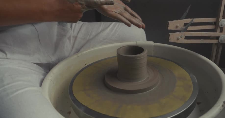 Hands refining the shape of a ceramic piece on a pottery wheel