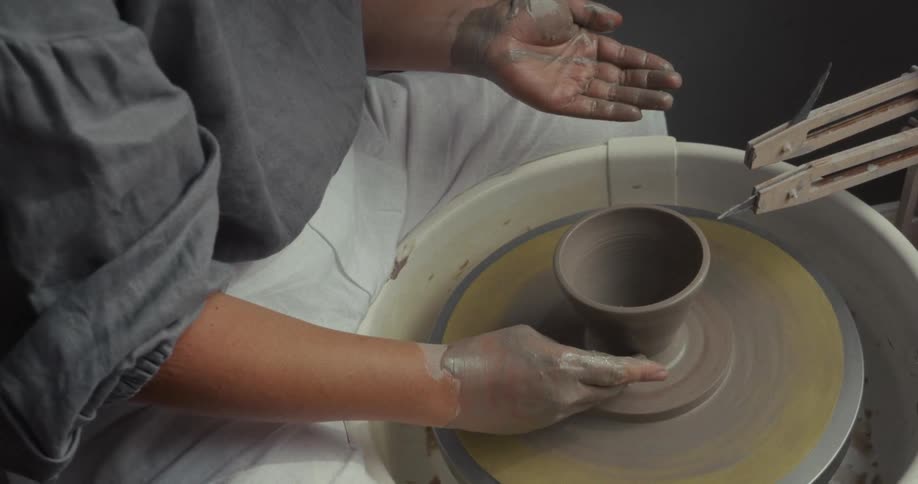 Hands shaping a clay vase on a pottery wheel