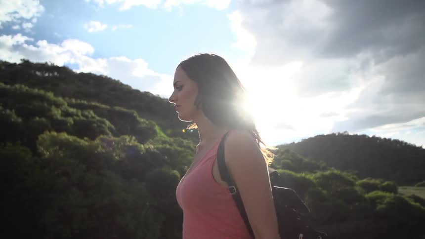 Woman walking near a grassy hillside on a cloudy day