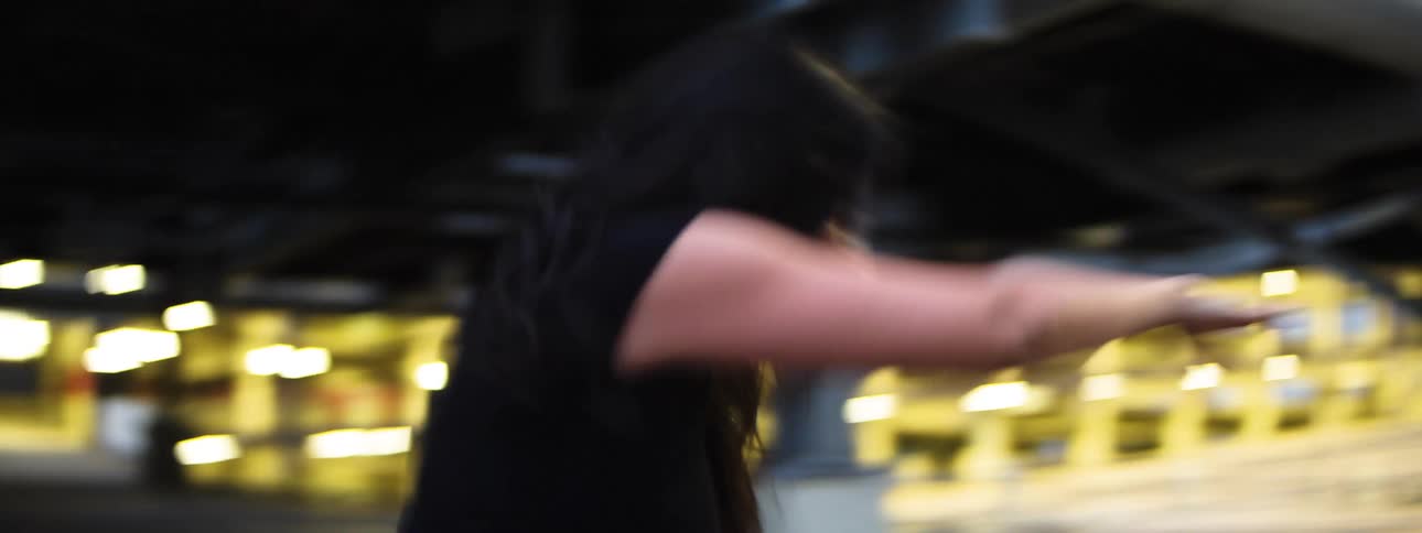 Woman dancing in intense motion under urban lights at dusk