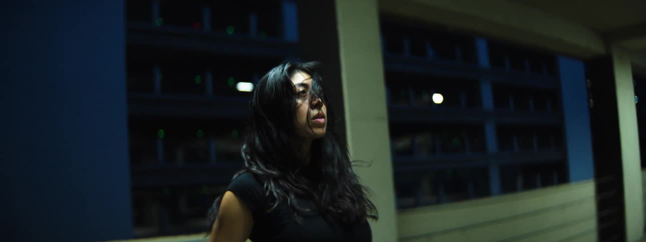 Woman dancing in a parking garage at night breaths heavily