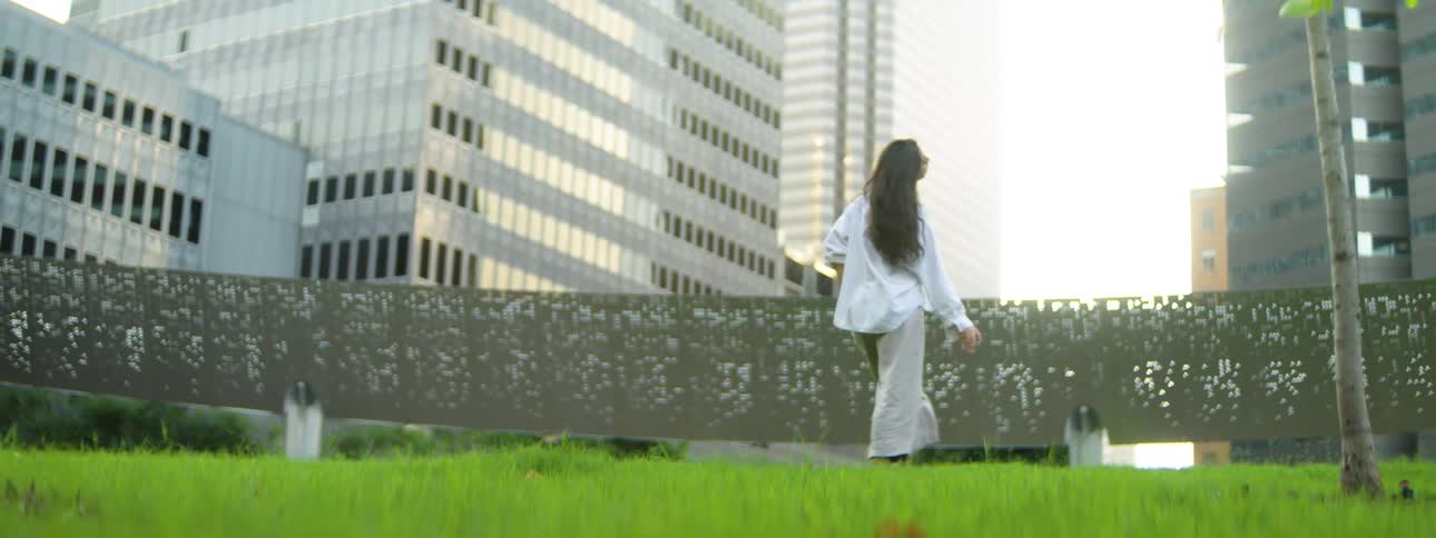A dark haired woman dance outdoors in an urban city area