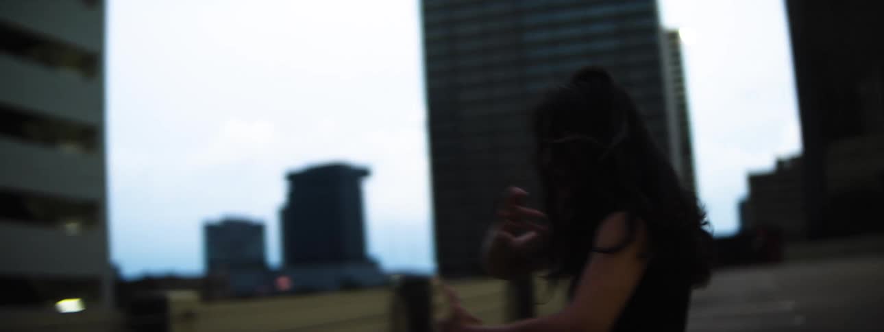 Female dancer dances while in an empty parking area downtown after dusk
