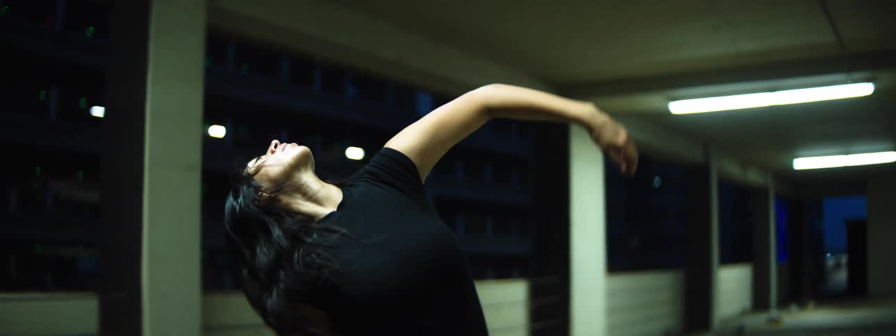 Woman dancing with expressive movements in an urban space at night
