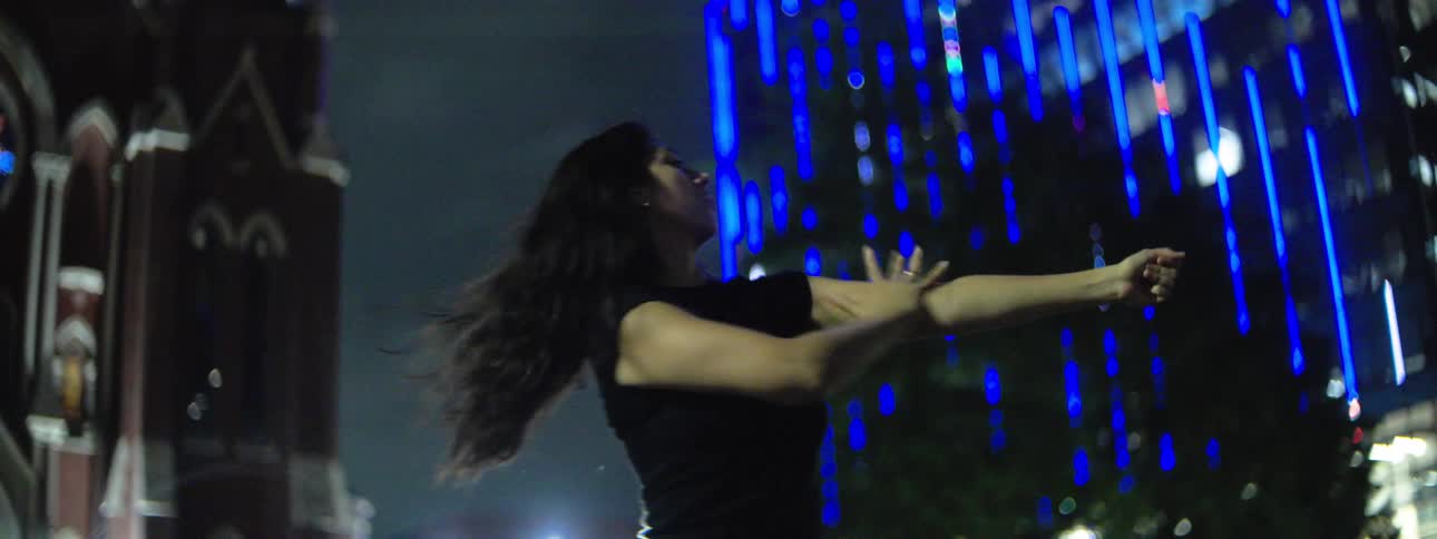 Woman dances outside at night near an urban cathedral