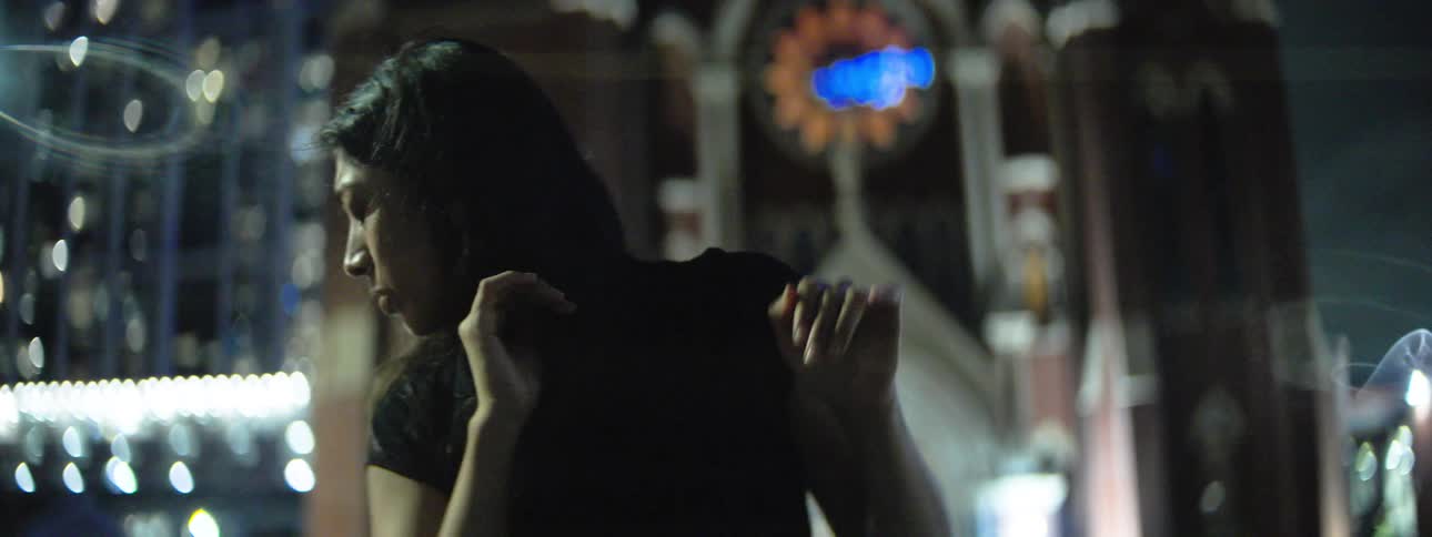 Woman dances outside near an urban cathedral at night