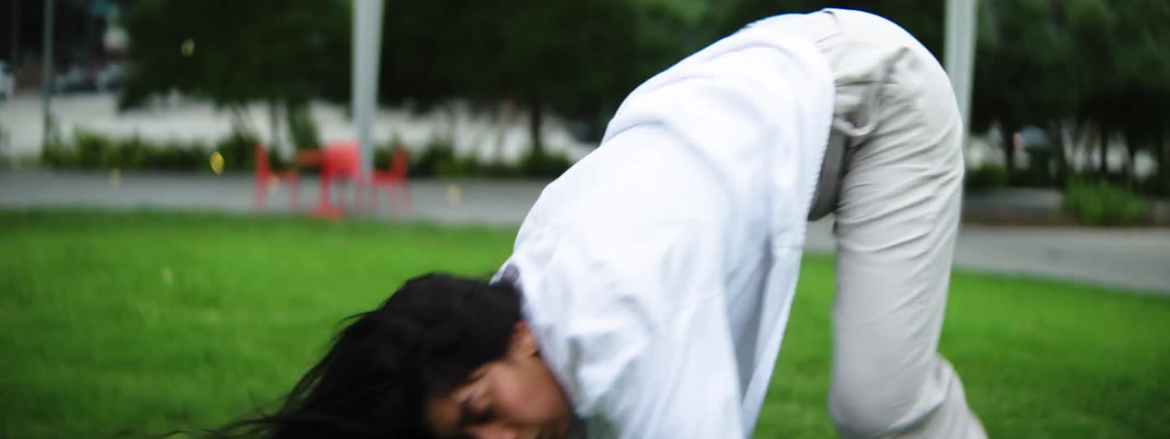A female dancing around erratically on grass in a major city