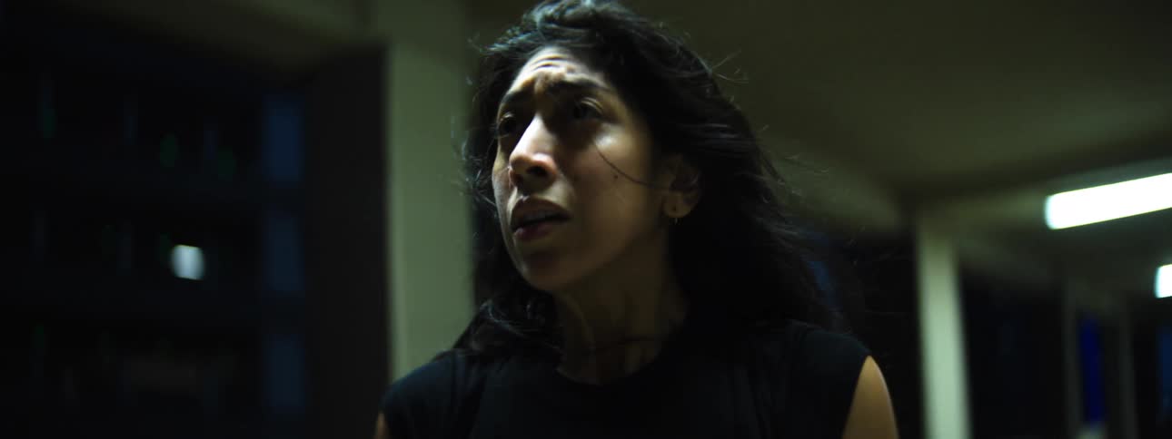 A female who appears to be sad and upset dances and moves erratically in a corridor at night