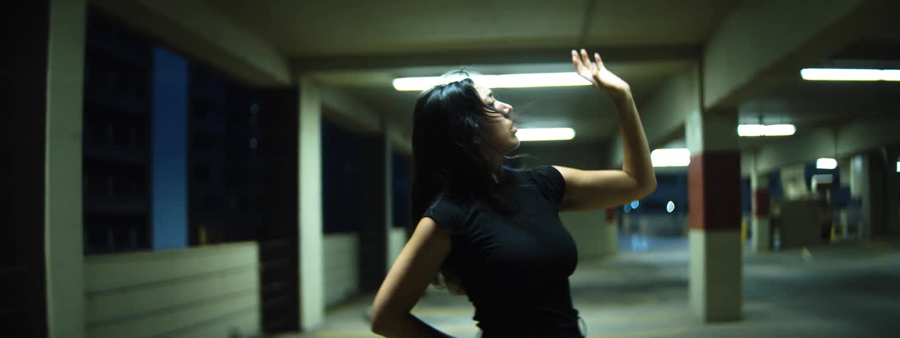 A female is dancing in a parking garage at night