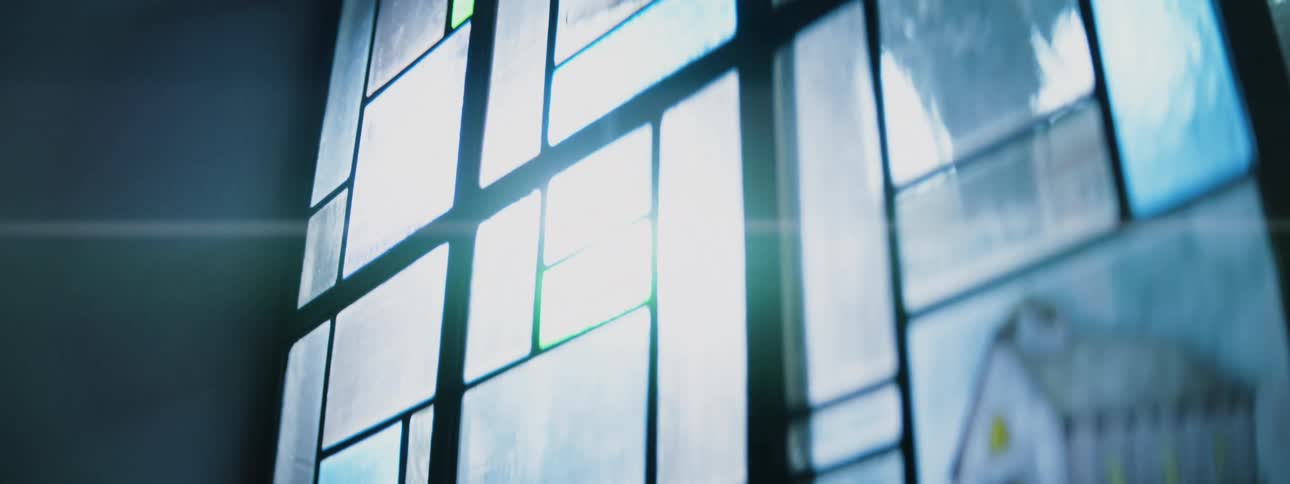 A closeup view focuses on a large multipaned stained glass window with an intense light source shining through