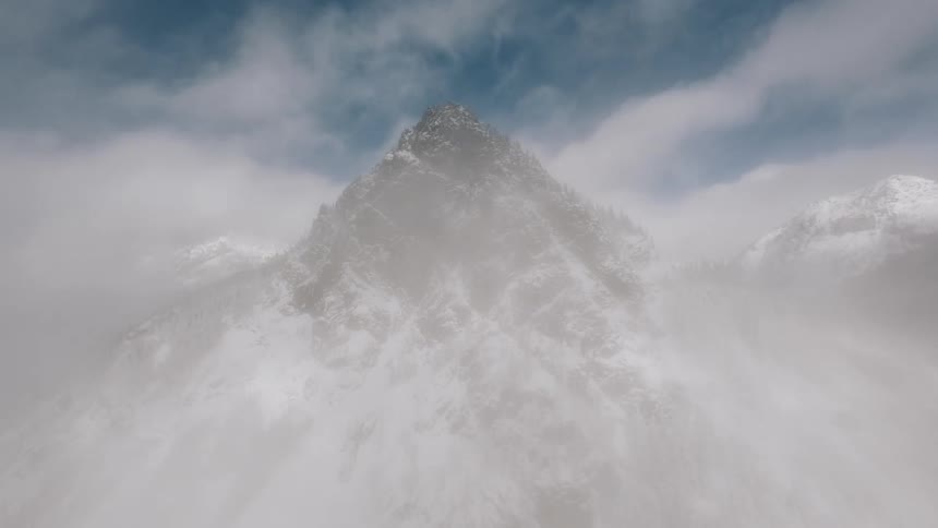 Windblown clouds swirl around a snowcovered mountain peak beneath patches of bright blue sky