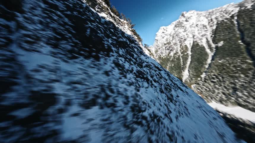 Speeding across a snow covered mountain side then a turn to dive then another turn to pull back and head upwards