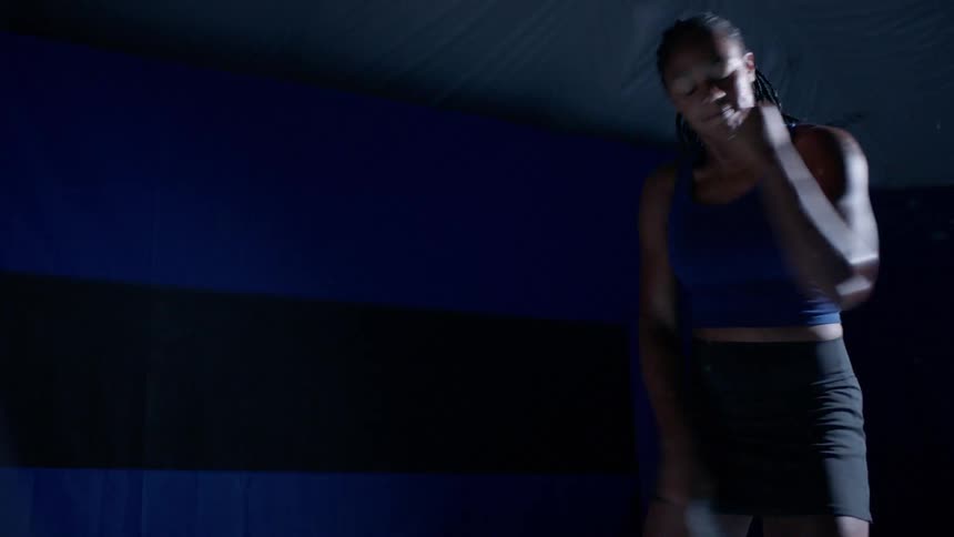 A black female is hitting a tennis ball with a tennis racket