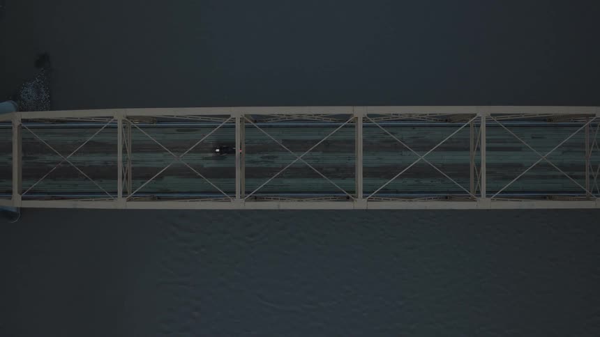 A motorcycle crosses a road bridge over a body of water