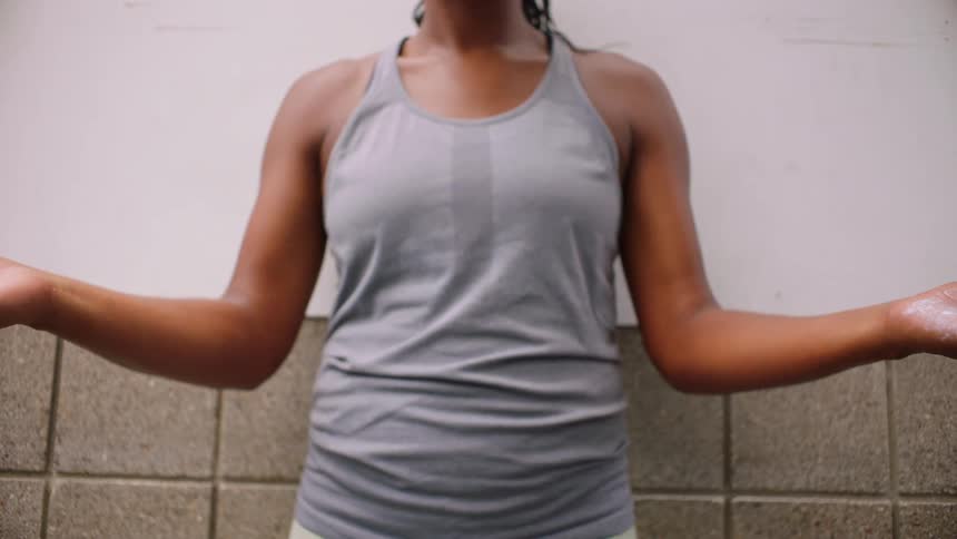Close up of a young black woman clapping with white powder in her palms while standing in a room