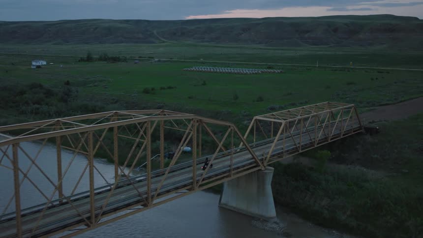Tracking Motorcycle from above as it crosses yellow bridge at sunset