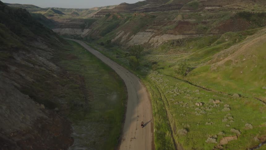 Aerial shot of a motorcycle traveling down a road in the badlands