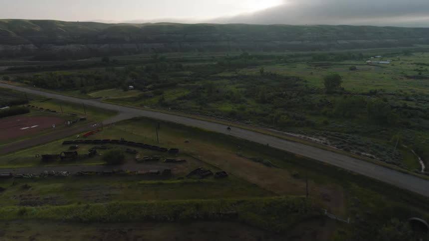 A motorcycle on a rural road passing fields small houses and headed towards a river